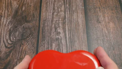Hands hold red box as heart on wooden background Stock Footage 145976024