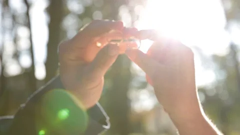 Hands hold rings close against the rays of the sun. Stock Footage 105670032