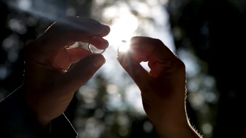 Hands hold rings close against the rays of the sun. Stock Footage 105670097