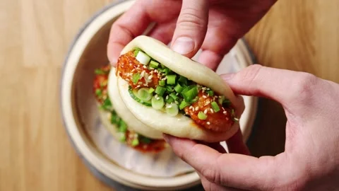 Hands hold shrimp bao close, showing shrimp coated in spicy sauce. Stock Footage 341733826