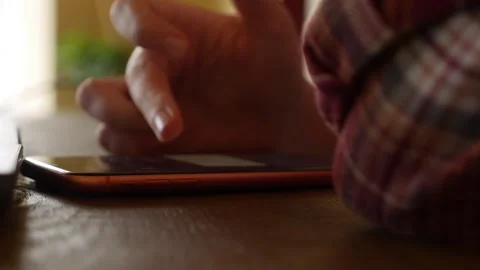 Hands hold a smartphone in a cafe setting as fingers move across the screen Stock Footage 325174261