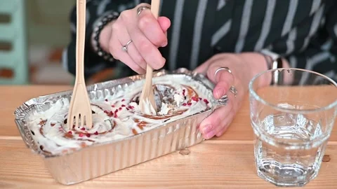 Hands hold spoons and dig into a dessert container filled with creamy layers. A Stock Footage 336778811