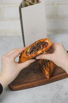Hands hold a stuffed flatbread with meat and vegetables inside Stock Photos