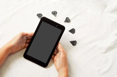 The hands hold the tablet. diamonds on the background. 스톡 사진