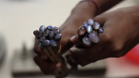 Hands hold two bundles of raw, untreated gemstones, highlighting their natural Video stock 331822289