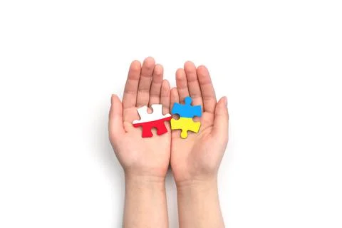 Hands hold two puzzles with flags of Poland and Ukraine on white background. Stock Photos