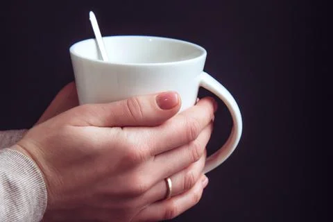 Hands hold a white ceramic cup with tea. Breakfast outside the home Stock Photos