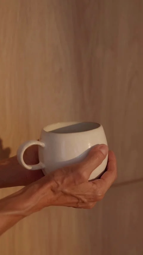 Hands hold white ceramic mug in soft warm light Vídeo Stock 331770022