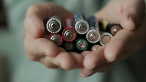 Hands holding alkaline batteries heap. Concept of Recycling, energy, power Stock Footage 166783553