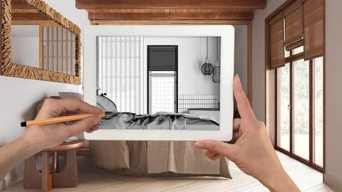 Hands holding and drawing on tablet showing wooden japandi bedroom details .. Ilustración de archivo