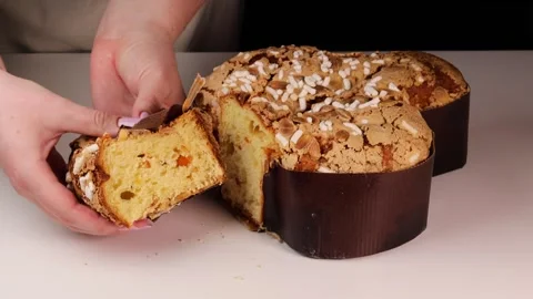 Hands holding and gently compressing a slice of colomba cake, highlighting the Stock Footage 306156711