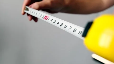 Hands holding and pull yellow measuring tape on grey background, close up. Stock Footage 253971416