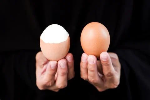 A hands holding and showcasing a partially peeled hard boiled egg on the le.. Stock Photos