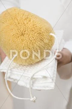 Hands Holding Bath Sponge On White Towel