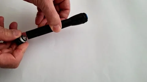 Hands Holding Black Flashlight Body and End Cap on White Stock Footage 332890597