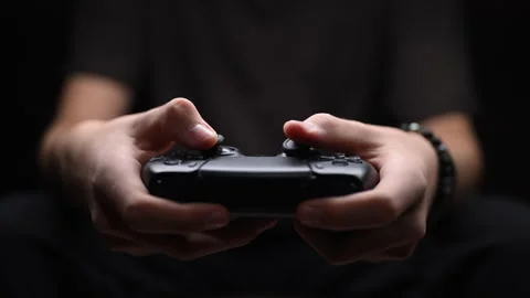 Hands holding black game controller, intense gameplay focus, dark background. Stock Footage 319141688