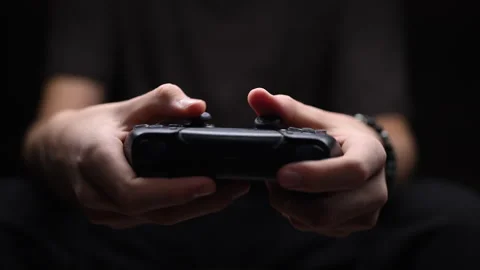 Hands holding black game controller, intense gameplay focus, dark background. Vídeos de archivo 319142394