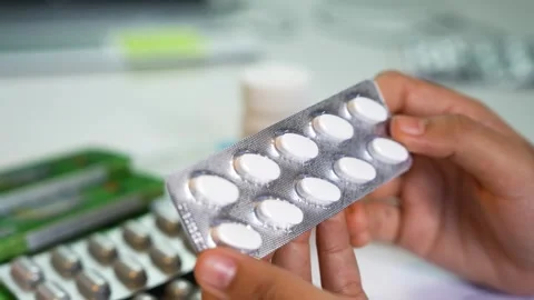 Hands holding blister pack of white tablets, Close-up of hands holding blis.. Vidéo 330547467
