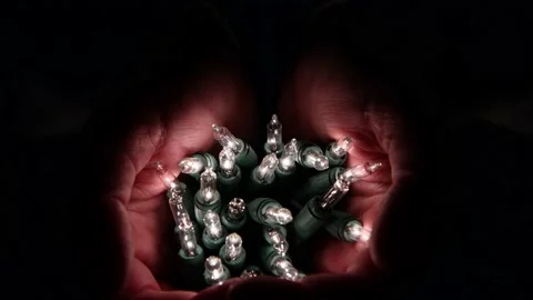 Hands holding a bunch of warm white glowing lights Stock Footage 163850372