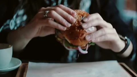 Hands holding burger with cafe setting. Video stock 305808148