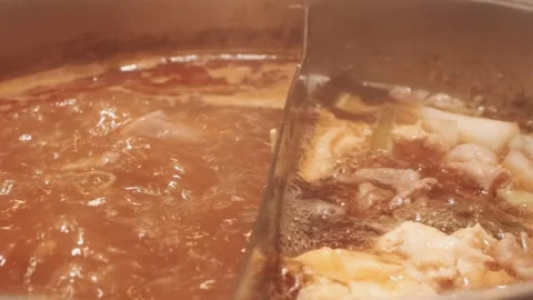 Hands holding chopsticks dipping a slice of pork into a bubbling shabu-shab.. Stockbeeldmateriaal 343613930