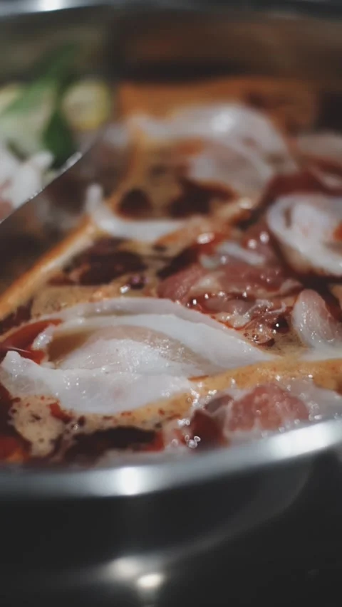 Hands holding chopsticks dipping a slice of pork into a bubbling shabu-shab.. Stock Footage 343613952
