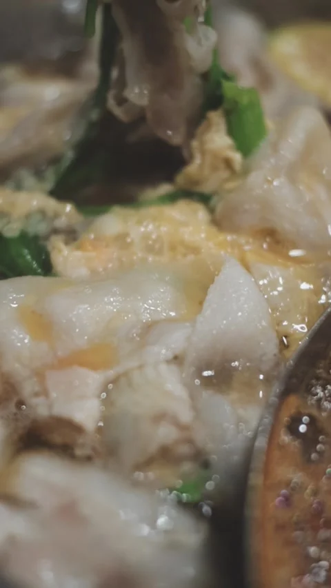 Hands holding chopsticks dipping a slice of pork into a bubbling shabu-shab.. 스톡 동영상 343613982
