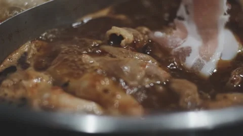 Hands holding chopsticks dipping a slice of pork into a bubbling shabu-shab.. Stock Footage 343614017