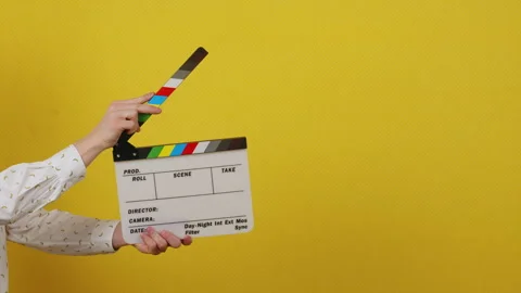 Hands holding a clapper board on a yellow isolated background Stock Footage 172039075