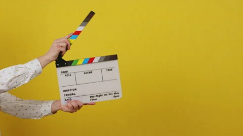 Hands holding a clapper board on a yellow isolated background Stock Footage 172039093