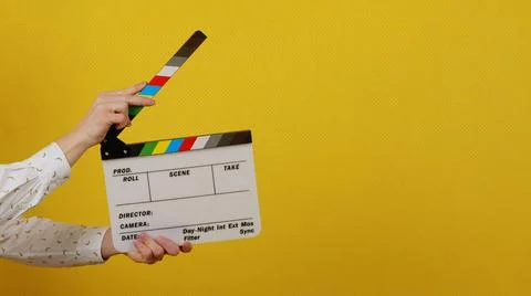 Hands holding a clapper board on a yellow isolated background Stock Photos