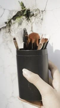 Hands holding clean black vector set of professional makeup Stock Photos