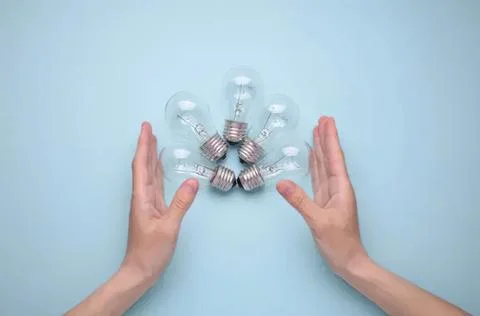 Hands holding clear light bulbs arranged in a circle Stock Photos