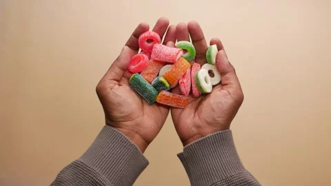 Hands holding colorful candy on plain background Stock Footage 341646452