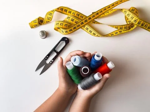 Hands holding colorful threads with scissors and measuring tape for sewing Stock Photos