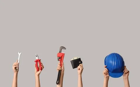 Hands holding construction tools, wallet with money, and blue hard hat on gra Stock Photos