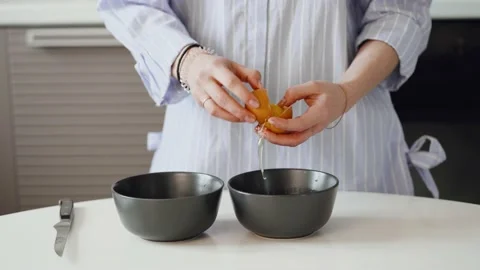 Hands holding a cracked brown egg and breaking, Close-up. Stock Footage 147342648