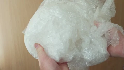 Hands holding crumpled bubble wrap, symbolizing the issue of plastic waste .. Stock Footage 316051107