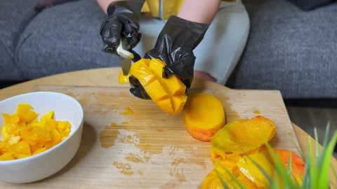 Hands Holding Cubed Mango Half with Black Gloves on Cutting Board Stock Footage 311418940