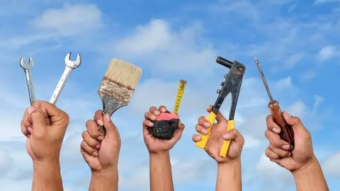 Hands holding different carpentry tools against blue sky background. Labor .. Stock Photos