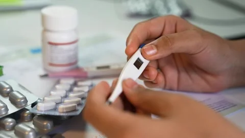 Hands holding digital thermometer with pills and medicine 库存影片 330547452
