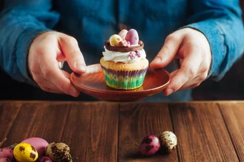 Hands holding Easter cupcake decorated with candy eggs in nest Stock Photos