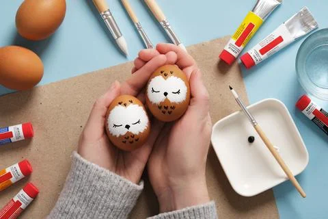 Hands holding Easter eggs with cute sleeping owls, hand-painted with acryli.. Stock Photos