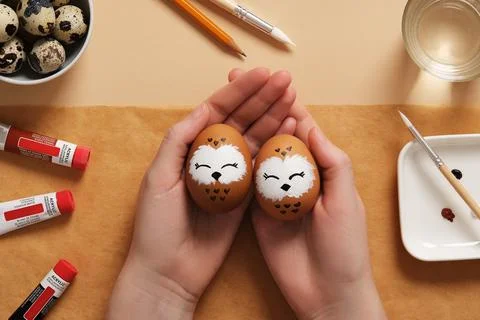 Hands holding Easter eggs with cute owls, hand-painted with acrylic paints, o Stock Photos