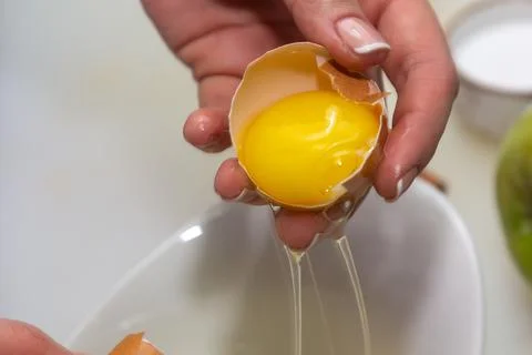 Hands holding egg shell with egg yolk separated Stock Photos