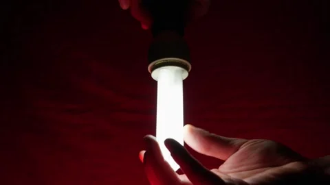 Hands Holding Flickering Fluorescent Lamp in Deep Red Lighting Stock Footage 334134081