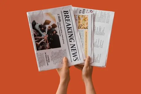 Hands holding a folded newspaper with breaking news headline Stock Photos