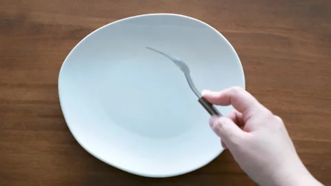 Hands holding a fork and knife next to an empty plate on wooden background. Stock Footage 290479102
