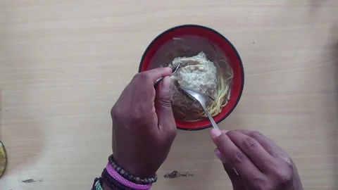 Hands holding a fork and spoon splitting a large meatball in a bowl Stock Footage 293185037