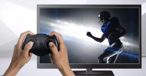 Hands holding gaming controller  with american football player on television Stock Photos